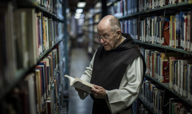 Priest reading from a book in the library