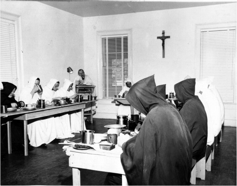 black and white photo of monks in hoods at table