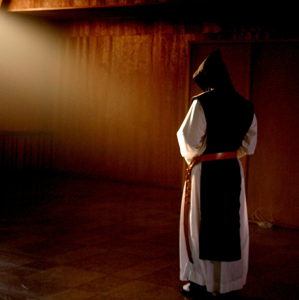 A Trappist Monk stands in a beam of light, contemplating God